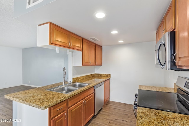 kitchen featuring stainless steel appliances, light hardwood / wood-style floors, kitchen peninsula, and sink