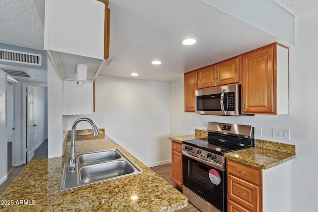 kitchen with stainless steel appliances, light stone counters, and sink