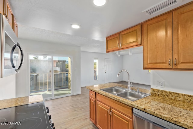 kitchen with light stone counters, sink, light hardwood / wood-style flooring, and stainless steel appliances