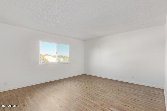 spare room with a textured ceiling and light hardwood / wood-style flooring