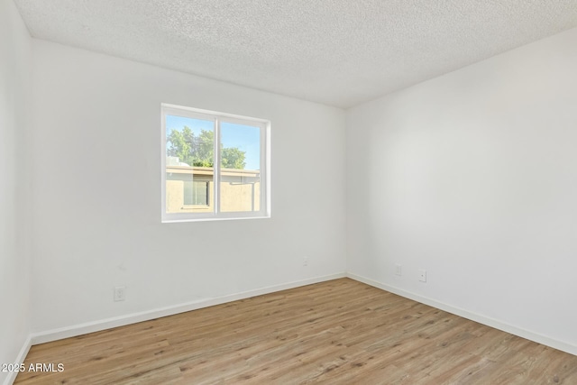 spare room featuring a textured ceiling and light hardwood / wood-style flooring