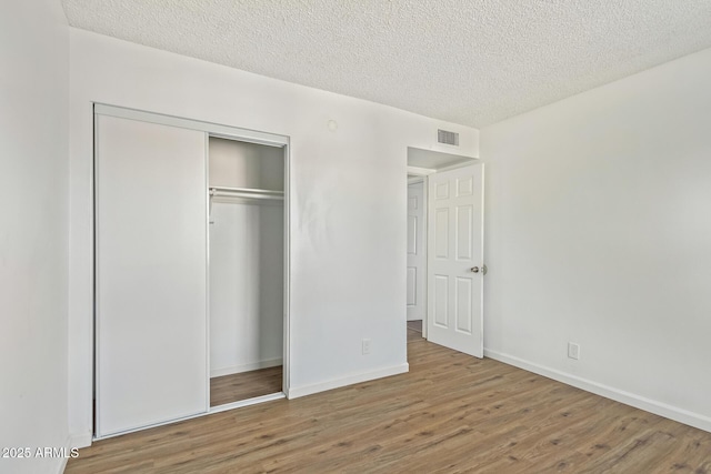 unfurnished bedroom with hardwood / wood-style floors, a closet, and a textured ceiling