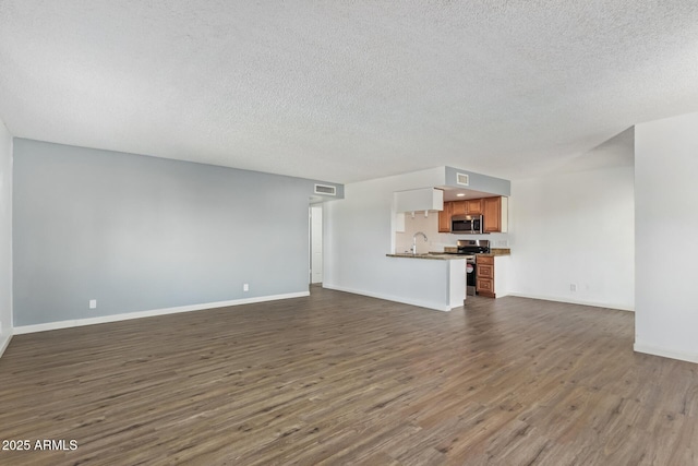 unfurnished living room with dark wood-type flooring, sink, and a textured ceiling