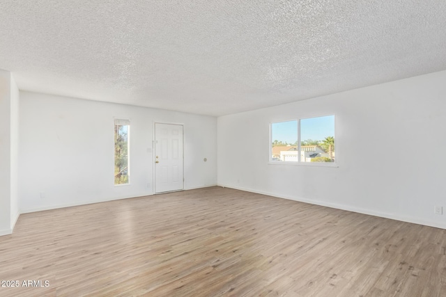 spare room with light hardwood / wood-style floors and a textured ceiling