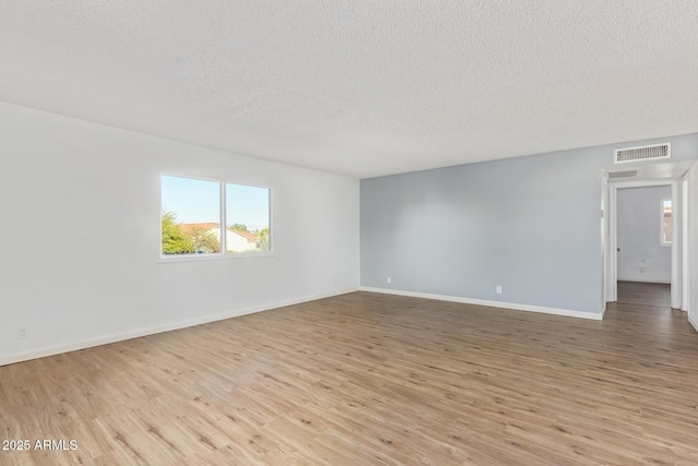 empty room with a textured ceiling and light hardwood / wood-style floors