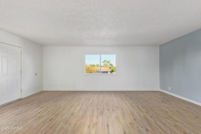 spare room with a textured ceiling and light hardwood / wood-style floors