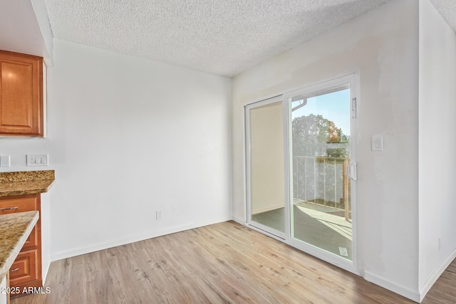 unfurnished dining area featuring a textured ceiling and light wood-type flooring