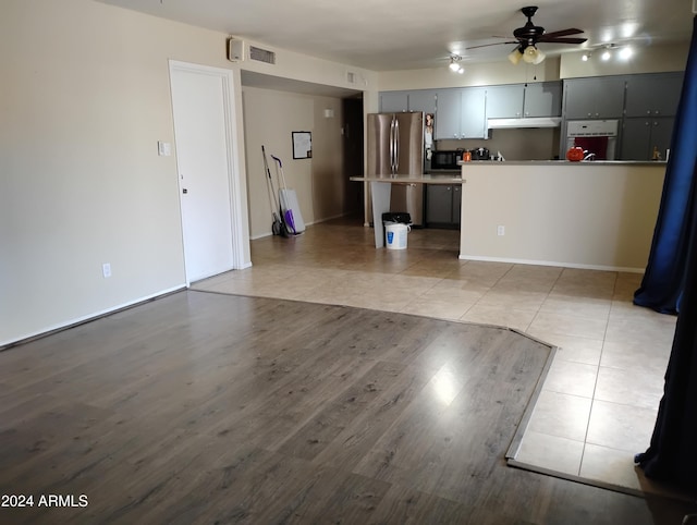 interior space featuring gray cabinetry, ceiling fan, stainless steel fridge, oven, and light tile patterned flooring