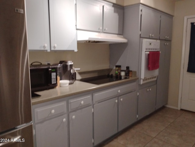 kitchen with white cabinets, light tile patterned floors, and black appliances