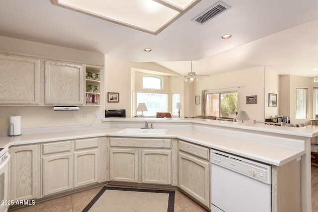 kitchen with white dishwasher, kitchen peninsula, sink, and light tile patterned floors