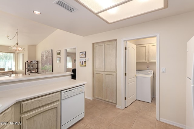 kitchen with light tile patterned flooring, washer / dryer, vaulted ceiling, hanging light fixtures, and white dishwasher