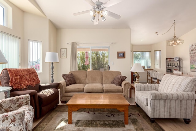 living room featuring ceiling fan with notable chandelier and hardwood / wood-style floors