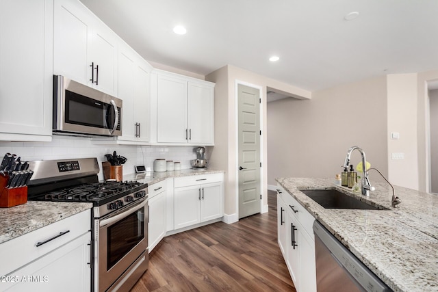 kitchen with sink, white cabinetry, light stone counters, stainless steel appliances, and decorative backsplash