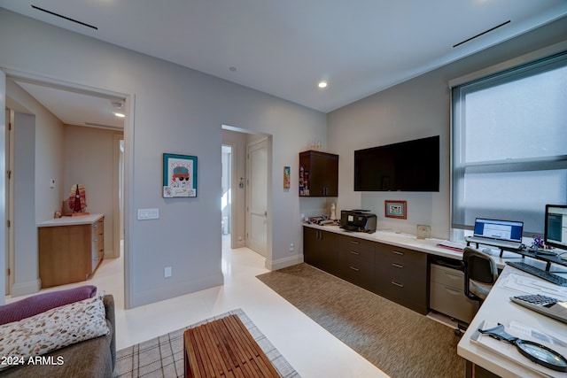 kitchen featuring dark brown cabinets, built in desk, and light tile patterned floors