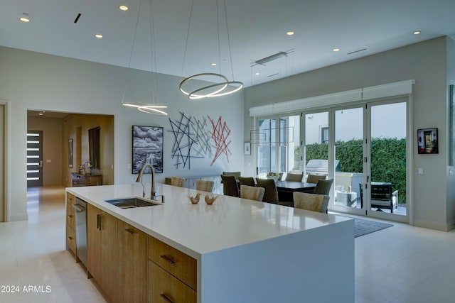 kitchen with a kitchen island with sink, sink, decorative light fixtures, and dishwasher