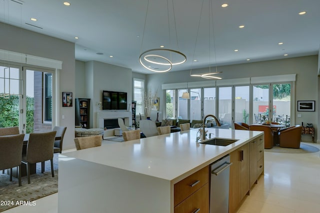 kitchen featuring decorative light fixtures, a kitchen island with sink, sink, and a healthy amount of sunlight