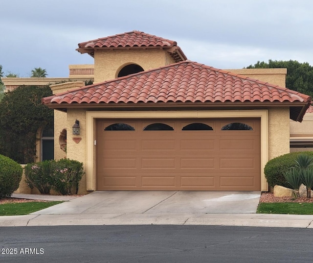 mediterranean / spanish house featuring concrete driveway, a tiled roof, an attached garage, and stucco siding