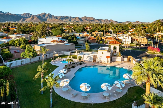 pool with a fenced backyard, a mountain view, and a patio