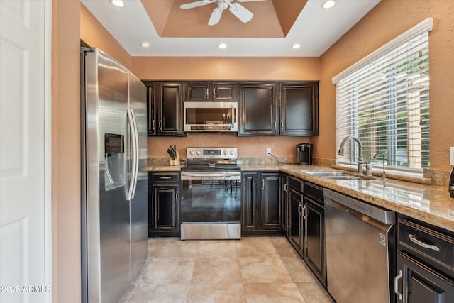 kitchen with light stone counters, light tile patterned floors, recessed lighting, appliances with stainless steel finishes, and a sink