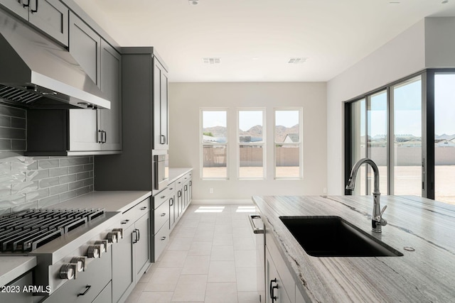 kitchen featuring gray cabinetry, sink, light tile patterned floors, tasteful backsplash, and stainless steel gas cooktop