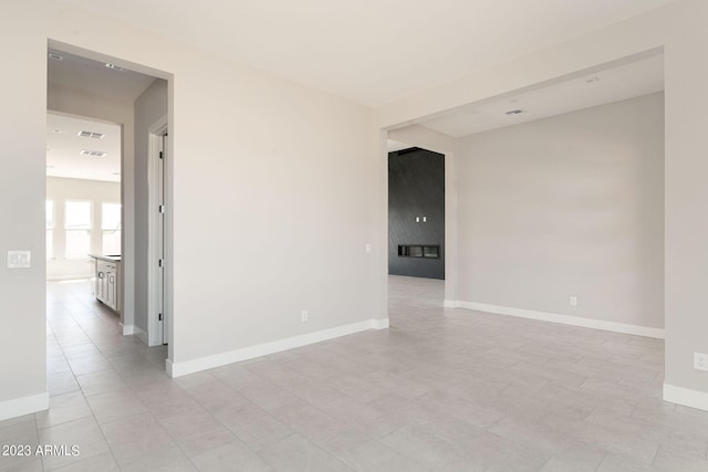 empty room featuring light tile patterned floors and a premium fireplace