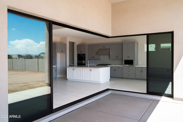 kitchen with sink, decorative backsplash, gray cabinets, built in microwave, and double oven