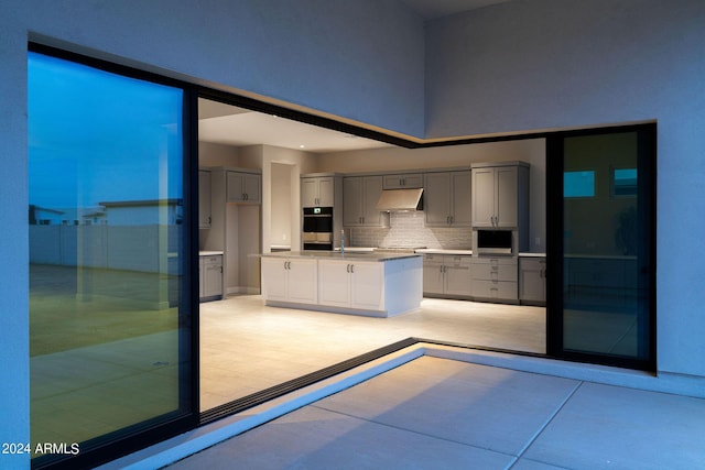 kitchen featuring tasteful backsplash, double wall oven, built in microwave, sink, and gray cabinets