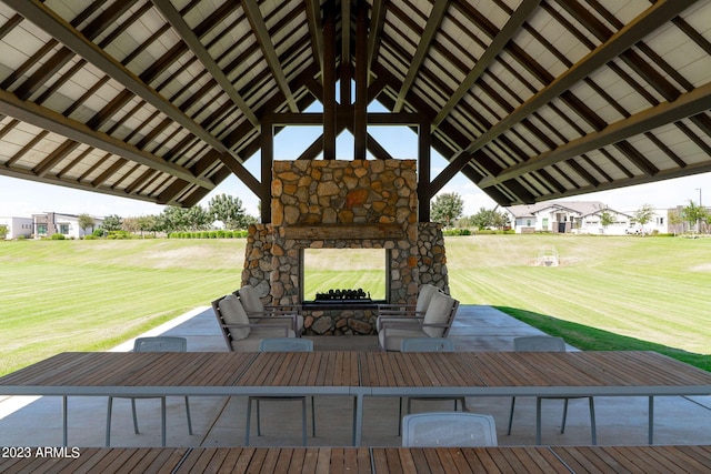 wooden terrace featuring a lawn and an outdoor stone fireplace