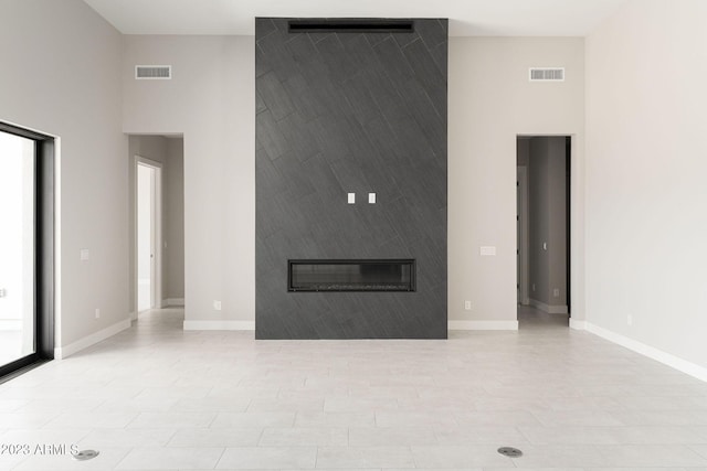 unfurnished living room with a large fireplace and a towering ceiling