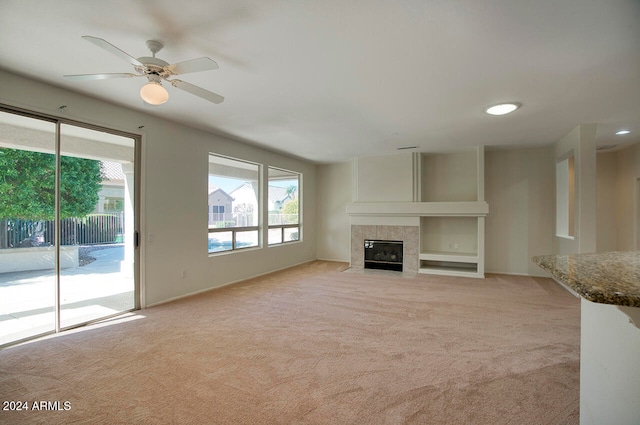 unfurnished living room with ceiling fan, light colored carpet, and a fireplace