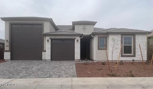 prairie-style home with decorative driveway and an attached garage