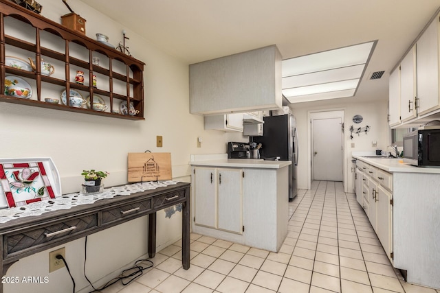 kitchen with light tile patterned floors, stainless steel appliances, sink, and white cabinets