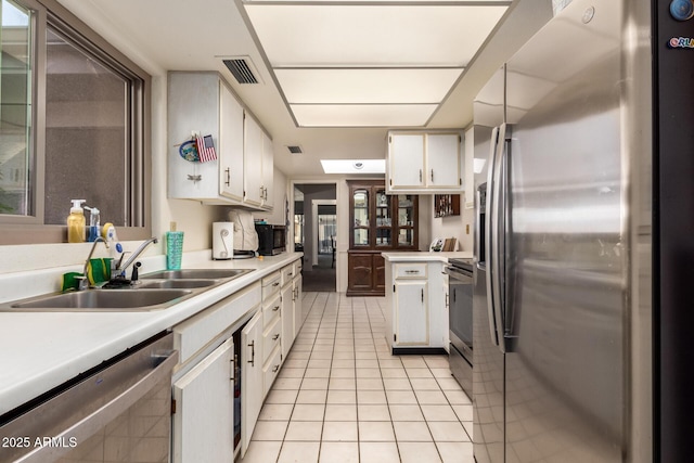 kitchen featuring light tile patterned flooring, appliances with stainless steel finishes, sink, and white cabinets