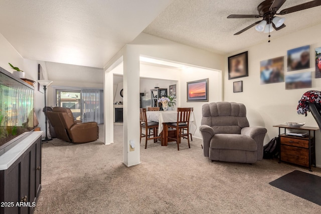 living room with ceiling fan, light carpet, and a textured ceiling