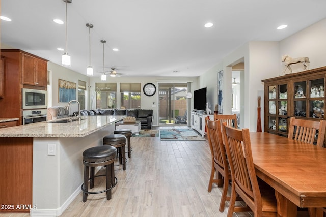 kitchen with built in microwave, sink, light stone counters, hanging light fixtures, and oven