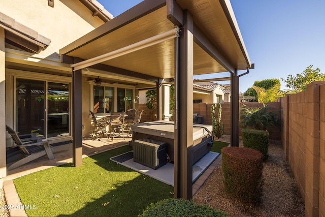 wooden terrace with a lawn, a hot tub, a patio, and ceiling fan