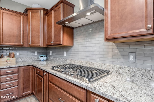 kitchen featuring light stone countertops, stainless steel gas cooktop, decorative backsplash, and exhaust hood