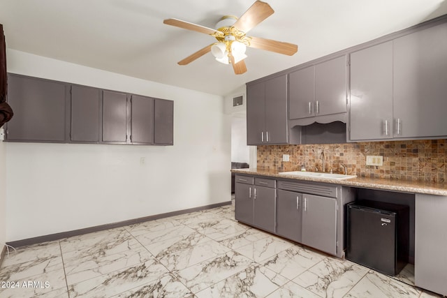 kitchen with sink, fridge, gray cabinets, ceiling fan, and backsplash