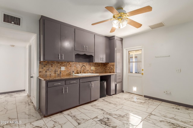 kitchen with dark stone countertops, decorative backsplash, sink, and ceiling fan