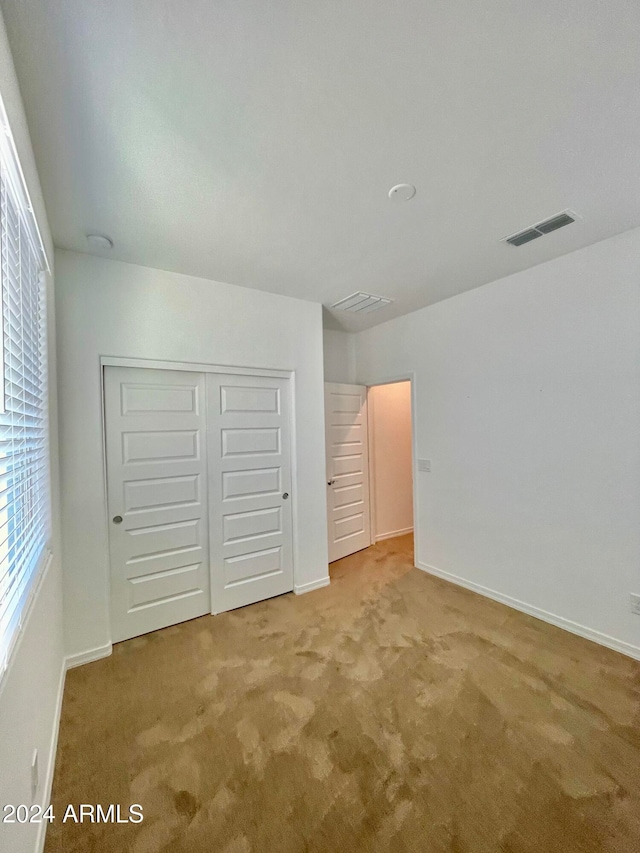 unfurnished bedroom featuring light colored carpet and a closet