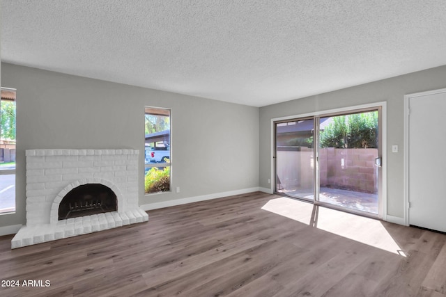 unfurnished living room with a textured ceiling, plenty of natural light, a fireplace, and wood-type flooring