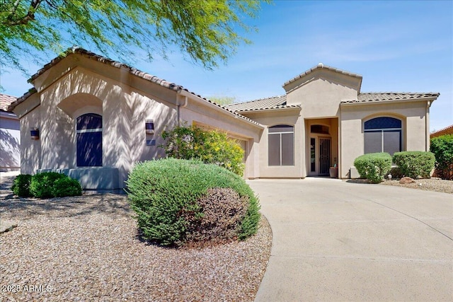 mediterranean / spanish-style home featuring stucco siding, a garage, driveway, and a tile roof