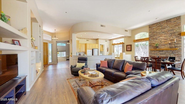 living room with built in shelves, light wood finished floors, and visible vents