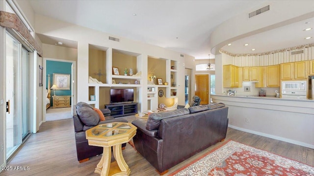 living room featuring light wood-type flooring, visible vents, and plenty of natural light
