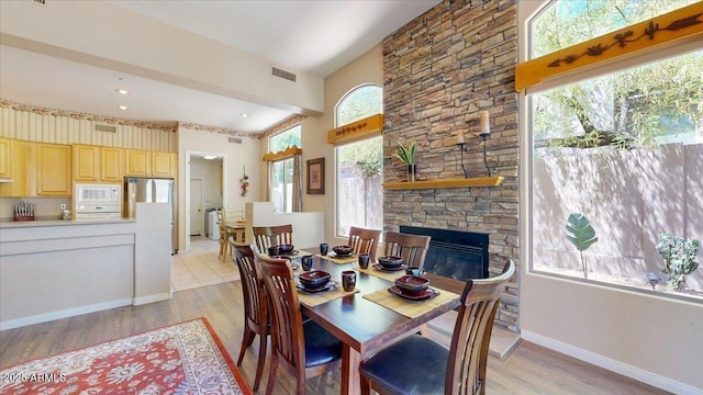 dining space featuring a fireplace, visible vents, light wood finished floors, and baseboards