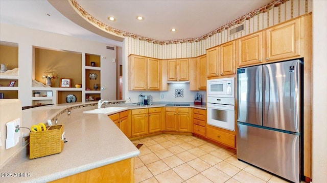 kitchen with light tile patterned floors, white appliances, light brown cabinetry, a peninsula, and light countertops