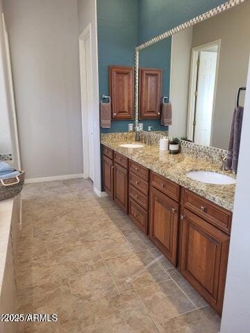 bathroom featuring double vanity, baseboards, and a sink
