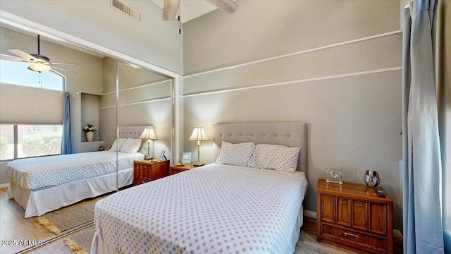 bedroom with a ceiling fan, visible vents, wood finished floors, and baseboards