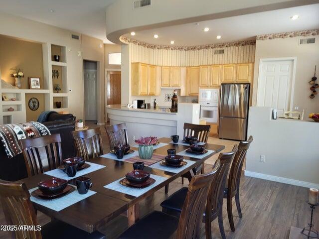 dining space featuring visible vents, wood finished floors, built in shelves, and recessed lighting