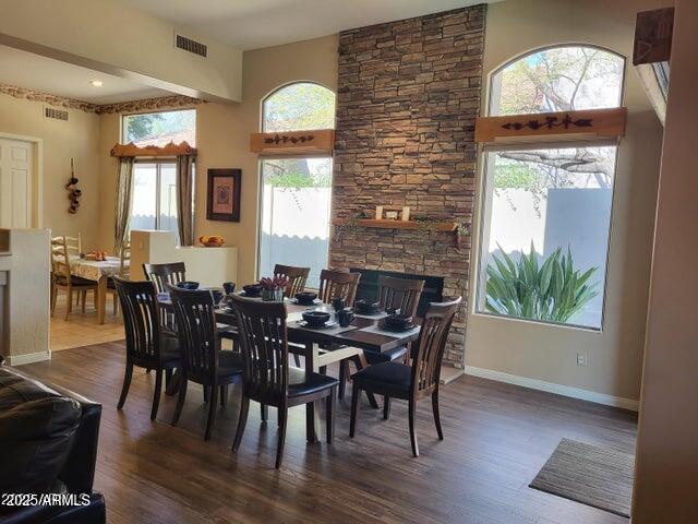 dining area with dark wood finished floors, visible vents, a towering ceiling, and baseboards